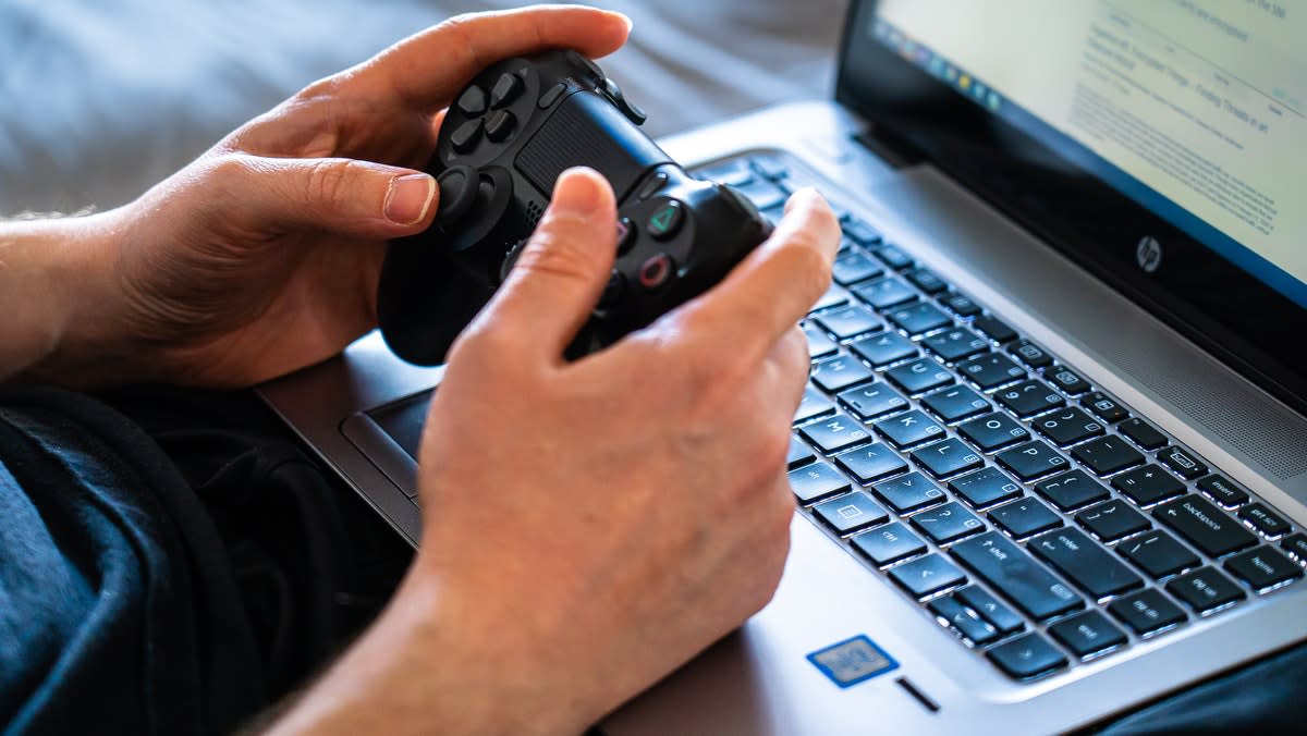 Two hands holding a video game controller over a keyboard