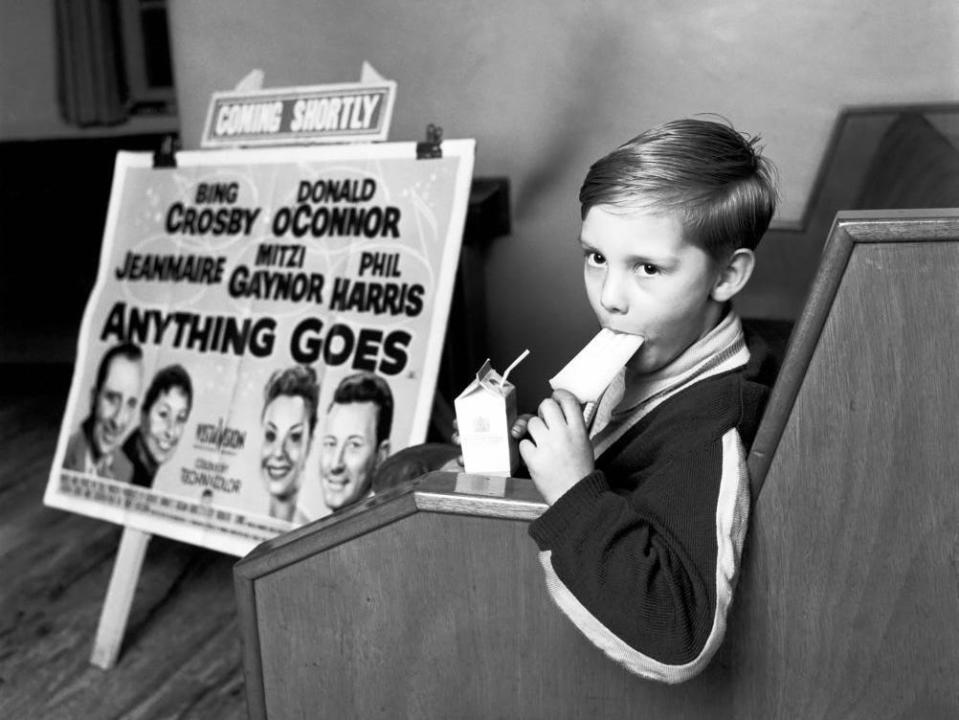 A young boy eats a popsicle at a movie theater in 1956