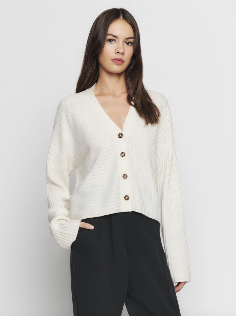 woman wearing black pants and white Trieste Regenerative Wool Cardigan (photo via Reformation)