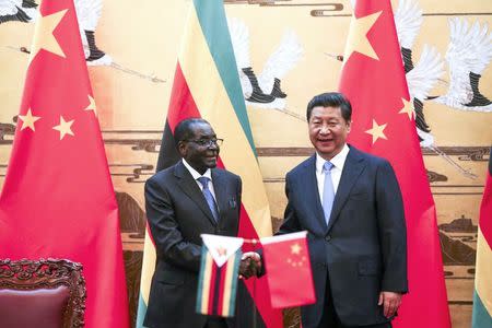 Zimbabwe's President Robert Mugabe (L) and his Chinese counterpart Xi Jinping shake hands during a signing ceremony at the Great Hall of the People in Beijing August 25, 2014. REUTERS/Diego Azubel/Pool