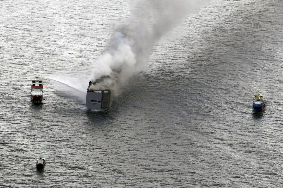 A boat hoses down the smoke from a fire which broke out on a freight ship in the North Sea, about 27 kilometers (17 miles) north of the Dutch island of Ameland, Wednesday, July 26, 2023. A fire on the freight ship Fremantle Highway, carrying nearly 3,000 cars, was burning out of control Wednesday in the North Sea, and the Dutch coast guard said it was working to save the vessel from sinking close to an important habitat for migratory birds. (Kustwacht Nederland/Coast Guard Netherlands via AP)