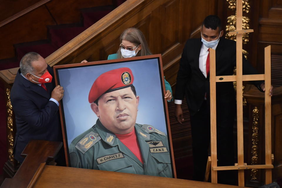 First Lady Cilia Flores, center, and Socialist party leader Diosdado Cabello, left, carry a portrait of late Venezuelan President Hugo Chavez into the chamber of the National Assembly as the ruling socialist party prepares to assume the leadership of Congress in Caracas, Venezuela, Tuesday, Jan. 5, 2021. Ruling party allies swept legislative elections last month boycotted by the opposition. (AP Photo/Matias Delacroix)