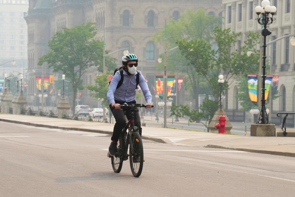 A cyclist wears a mask due to poor air quality conditions as smoke from wildfires in Ontario and Quebec hangs over Ottawa on Tuesday, June 6, 2023.