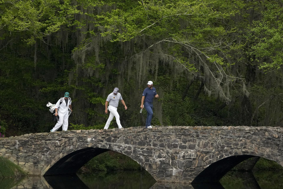 Dustin Johnson, right, and Lee Westwood, of England, walk across the Hogan Bridge during the second round of the Masters golf tournament on Friday, April 9, 2021, in Augusta, Ga. (AP Photo/Charlie Riedel)