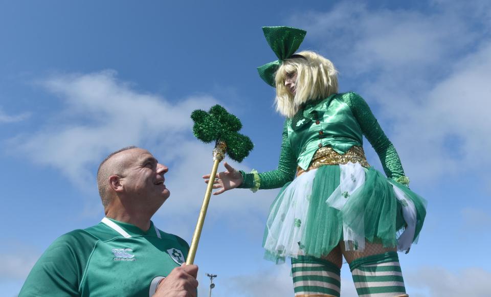 State Rep Tim Whelan helps out Allison Scott with her shamrock after she donned a pair of three-foot-tall stilts bringing her up to eight feet in height at the St. Patrick's Day Parade in 2021. This year, Whelan is grand marshal, leading the parade on Saturday.