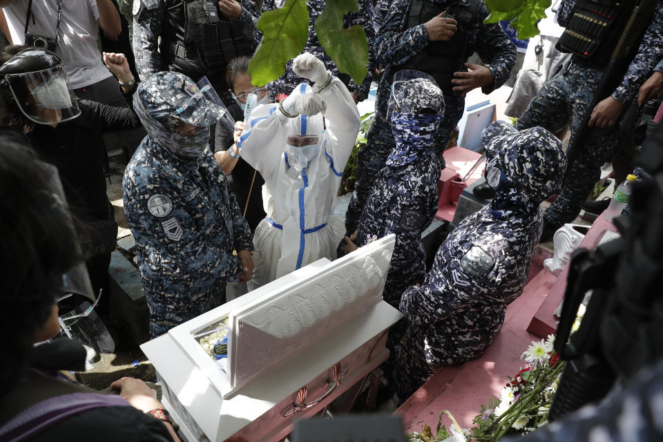 Detained left-wing activist Reina Mae Nasino in handcuffs and wearing a protective suit to prevent the spread of the coronavirus raises her clenched fists during funeral rites for her three-month-old firstborn named River at Manila's North Cemetery, Philippines on Friday Oct. 16, 2020. Left-wing groups on Friday decried as brutal the treatment of a detained activist, who was allowed by a Manila court to attend her baby's burial but was restrained with handcuffs, a sweltering protective suit and swarms of armed escorts as she quietly wept. (AP Photo/Aaron Favila)