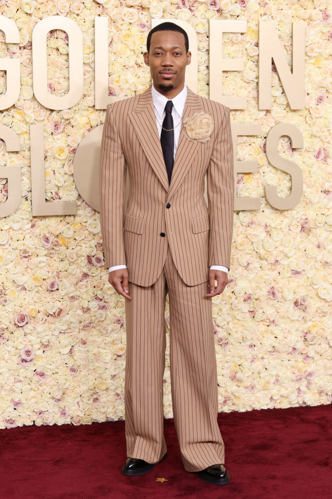 He's wearing a striped suit and tie with large corsage