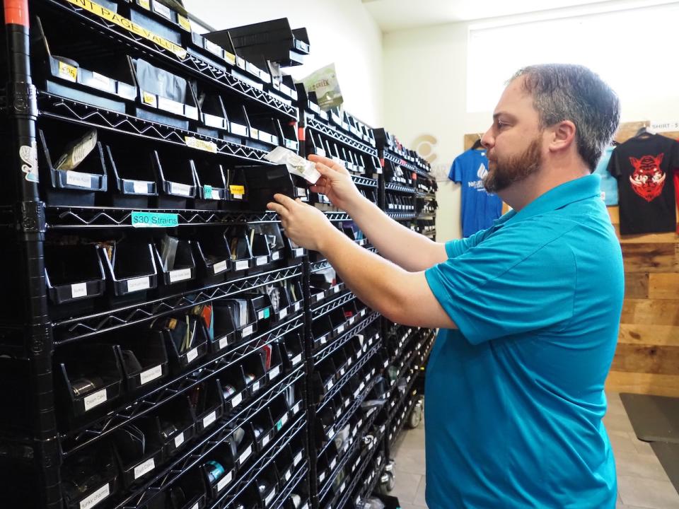  David Berman, manager of Natural Relief Dispensary in Sherwood, pulls a product from a shelf near the register on May 9, 2024. (Mary Hennigan/Arkansas Advocate)