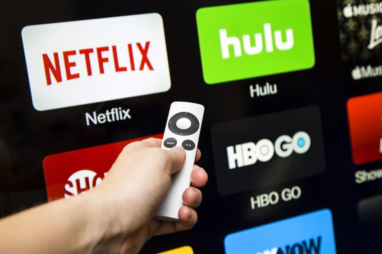 hand and remote in front of tv with hob go, showtime, hulu, and netflix
