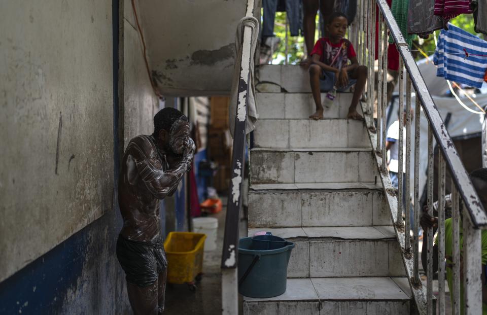 A person takes a bath at a public school that serves as a shelter for people displaced from their homes due to clashes between armed gangs in Port-au-Prince, Haiti, Monday, April 22, 2024. Haiti's health system has long been fragile, but it's now nearing total collapse after gangs launched coordinated attacks on Feb. 29, targeting critical state infrastructure in the capital and beyond. (AP Photo/Ramon Espinosa )