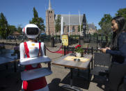 Leah Hu uses a tablet to demonstrate the use of a robot for serving purposes or for dirty dishes collection, as part of a tryout of measures to respect social distancing and help curb the spread of the COVID-19 coronavirus, at the family's Royal Palace restaurant in Renesse, south-western Netherlands, Wednesday, May 27, 2020. (AP Photo/Peter Dejong)