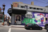 People make their way past a Chinatown talking portrait banner and mural in San Francisco, Monday, May 23, 2022. Chinatowns and other Asian American enclaves across the U.S. are using art and culture to show they are safe and vibrant hubs nearly three years after the start of the pandemic. From an inaugural arts festival in San Francisco to night markets in New York City, the rise in anti-Asian hate crimes has re-energized these communities and drawn allies and younger generations of Asian and Pacific Islander Americans. (AP Photo/Eric Risberg)