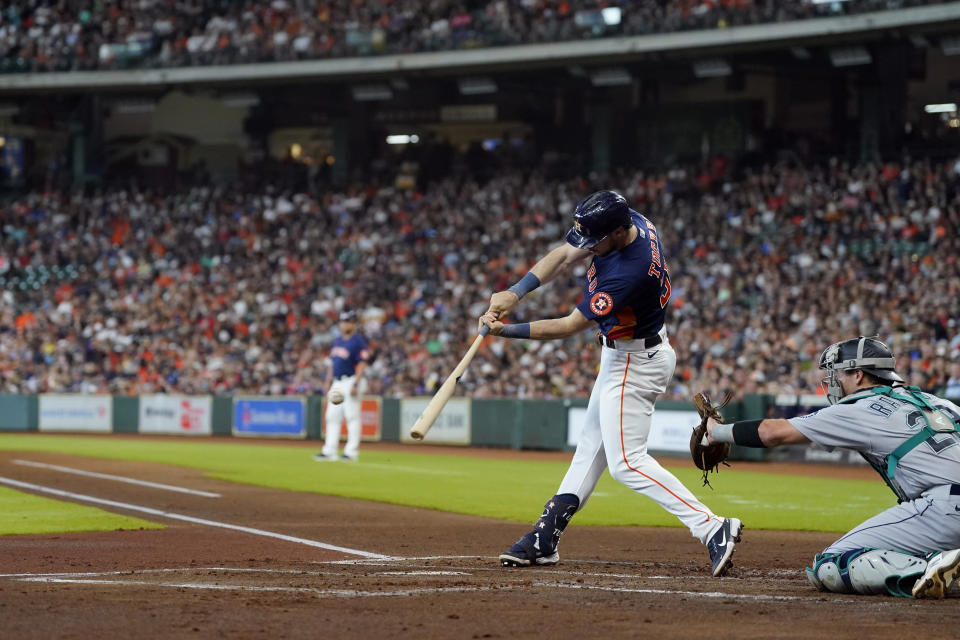 Houston Astros' Kyle Tucker (30) hits a RBI-single as Seattle Mariners catcher Cal Raleigh (29) reaches for the pitch during the first inning of a baseball game Sunday, July 31, 2022, in Houston. (AP Photo/David J. Phillip)