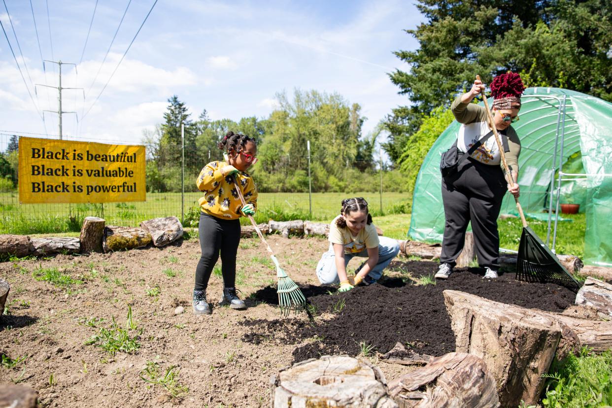 Jasmine Wilder and her daughters Zadera, 4, left, and Marley, 9, even out the dirt for wildflowers at Black Joy Farm on Sunday, April 21, 2024, in Keizer, Ore. "Honestly it has been life changing having acccess to this land, it's one thing reading about how important it is to cultivate the earth but actually having the space and being able to take them here is really special," said Wilder.