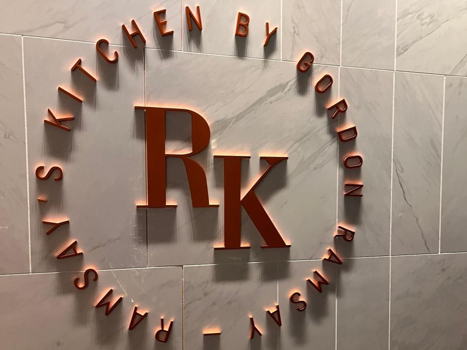 "RK" text on wall with "Ramsay's Kitchen by Gordon Ramsay" surrounding initials