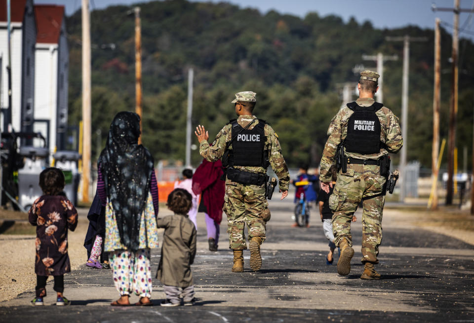 FILE - U.S. Military Police walk past Afghan refugees at the Village at the Ft. McCoy U.S. Army base on Sept. 30, 2021 in Ft. McCoy, Wis. Military bases that housed tens of thousands of Afghan refugees after the U.S. airlifted them out of Kabul last year incurred almost $260 million in damages that in some cases rendered buildings unusable for troops until they get significant repairs to walls and plumbing, the Pentagon’s inspector general found. Tens of thousands of Afghan refugees were flown to eight military bases in the U.S. where many of them lived for months while they waited fro visa processing and resettlement. (Barbara Davidson/Pool Photo via AP, File)