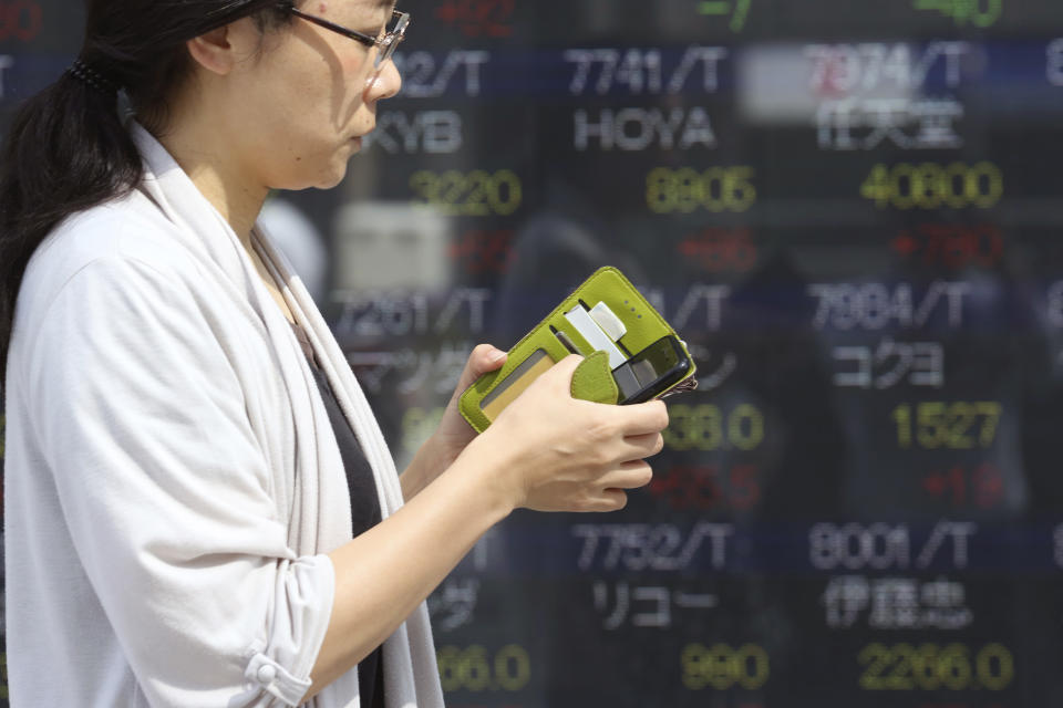 A woman walks by an electronic stock board of a securities firm in Tokyo, Tuesday, Oct. 1, 2019. Shares rose in Asia on Tuesday, with markets in Hong Kong and Shanghai closed for a national day holiday. (AP Photo/Koji Sasahara)