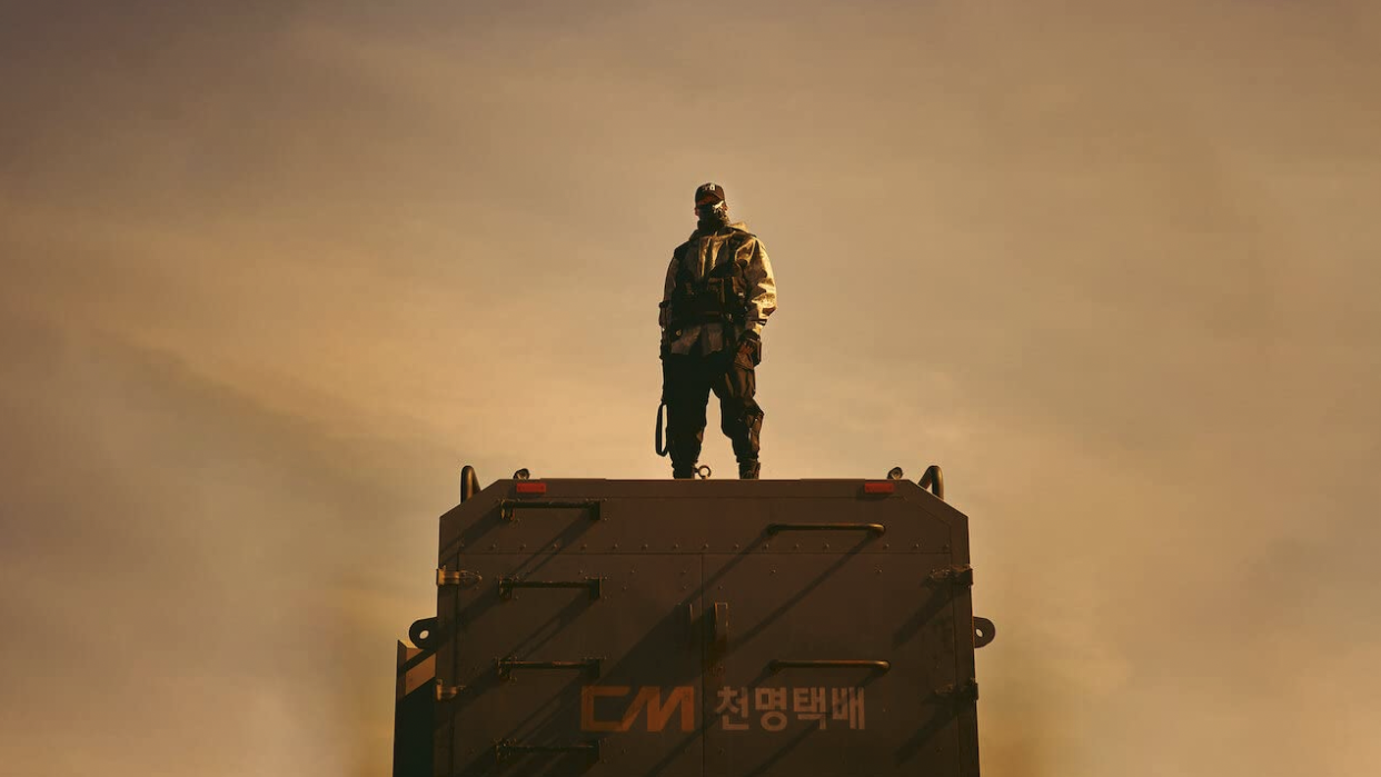  Masked figure stands on truck in desert 