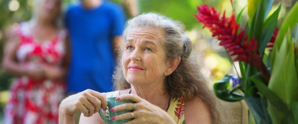 Forgetful older mother with cup near couple