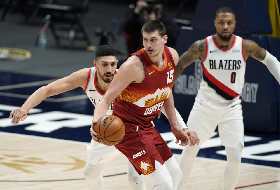 Denver Nuggets center Nikola Jokic, front, is defended by Portland Trail Blazers center Enes Kanter and guard Damian Lillard during the second half of an NBA basketball game Tuesday, Feb. 23, 2021, in Denver. The Nuggets won 111-106. (AP Photo/David Zalubowski)