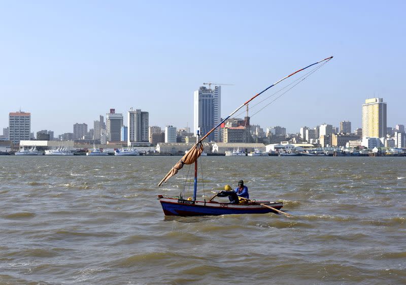 FILE PHOTO: Traditional fishing boat sails as Mozambique's tuna fleet sits in dock beneath Maputo's skyline