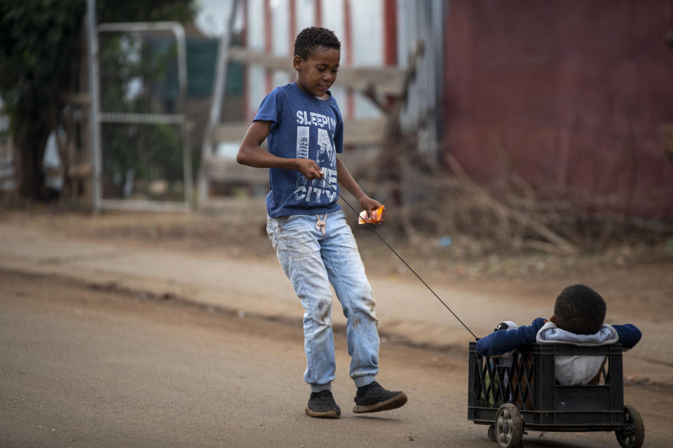 A young boy plays with his brother on the street in Thokoza, east of Johannesburg, South Africa, Friday, April 3, 2020. South Africa went into a nationwide lockdown for 21 days in an effort to control the spread of the coronavirus. The new coronavirus causes mild or moderate symptoms for most people, but for some, especially older adults and people with existing health problems, it can cause more severe illness or death. (AP Photo/Themba Hadebe)