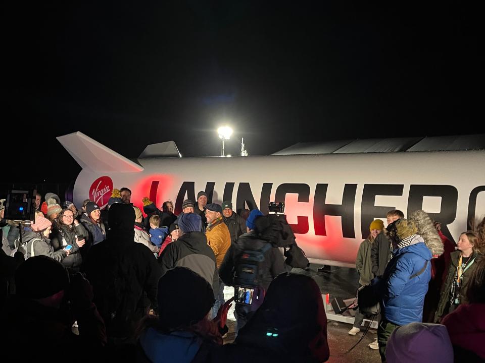 Broadcast crew around replica of LauncherOne rocket.