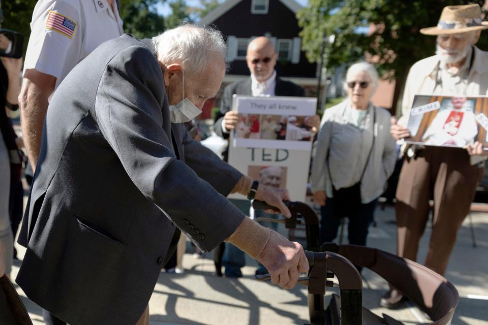 Demonstrators watch as former Cardinal Theodore McCarrick leaves Dedham District Court after his arraignment on Sept. 3, 2021, in Dedham, Mass. McCarrick pleaded not guilty to sexually assaulting a 16-year-old boy during a wedding reception in Massachusetts nearly 50 years ago.