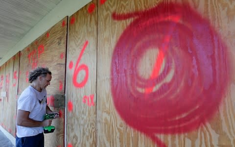 Erik Budman drills a nail into the plywood as he prepares for Hurricane Irma - Credit: Alan Diaz/AP