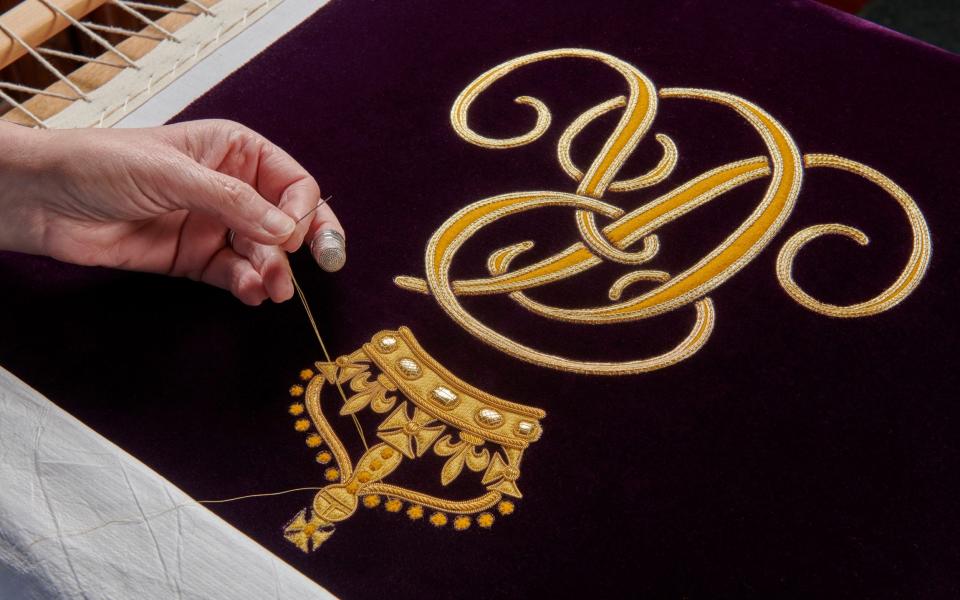 A member of the Royal School of Needlework hand-embroidering the Queen’s cypher onto her Robe of Estate - Royal School of Needlework