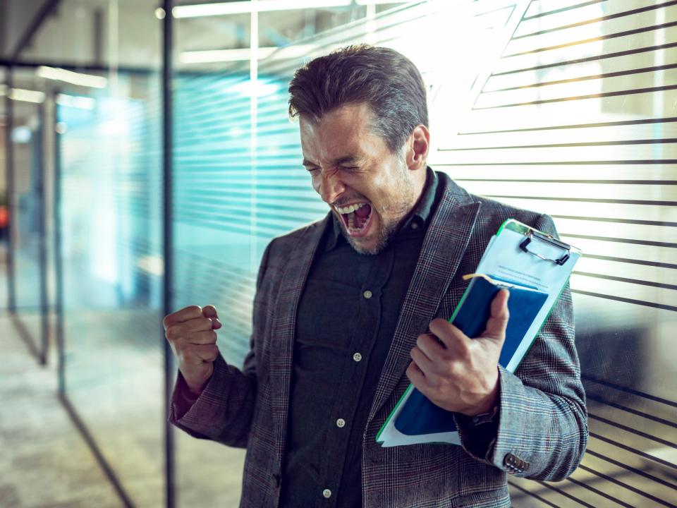 man with closed eyes and clenched fists celebrates in an office