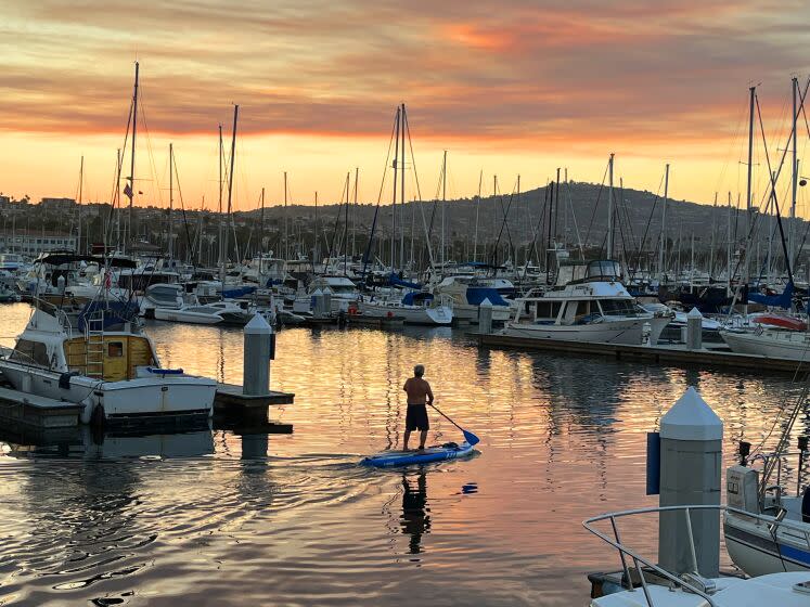 A padddle baordwer in the San Pedro marina under a smoky sunset, due to the wildfires in Southern California on Labor Day 2022.