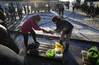 Women wash children's clothes with cold water at the "Bruzgi" checkpoint logistics center at the Belarus-Poland border near Grodno, Belarus, Wednesday, Dec. 22, 2021. Since Nov. 8, a large group of migrants, mostly Iraqi Kurds, has been stranded at a border crossing with Poland. Most of them are fleeing conflict or hopelessness at home, and aim to reach Western European countries. But as temperatures fall below freezing, life at the border becomes more challenging. (AP Photo/Pavel Golovkin)