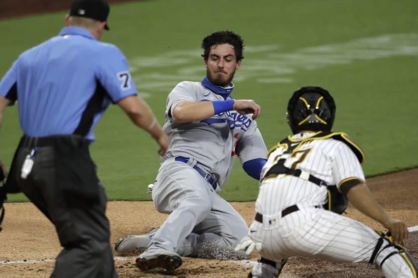 Los Angeles Dodgers' Cody Bellinger, center, scores off a single by Corey Seager as San Diego Padres catcher Francisco Mejia, right, is late with the tag during the sixth inning of a baseball game Tuesday, Aug. 4, 2020, in San Diego. Los Angeles Dodgers' Justin Turner also scored on the play, and San Diego Padres center fielder Trent Grisham picked up a throwing error. (AP Photo/Gregory Bull)