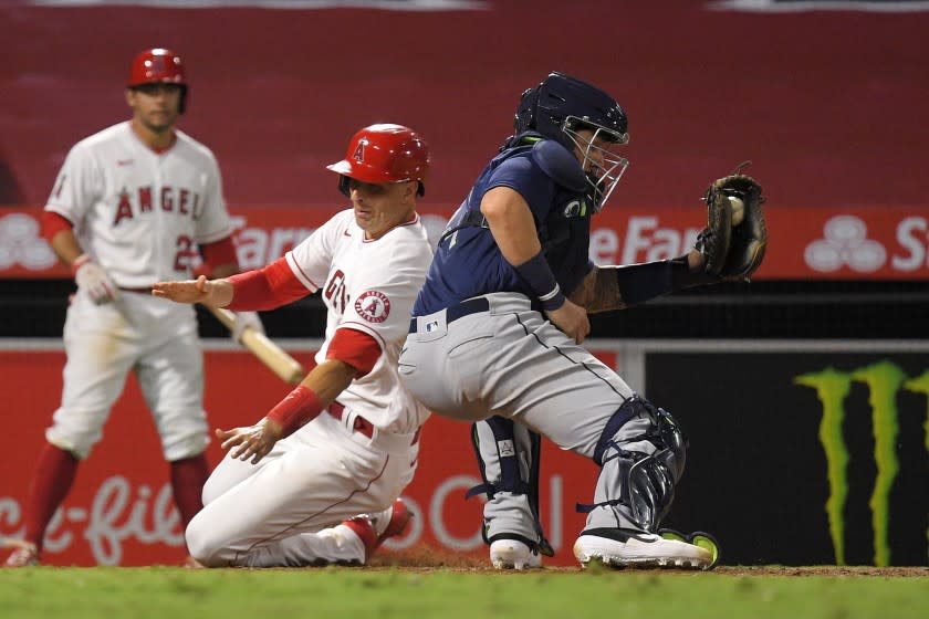 Los Angeles Angels' Jason Castro, center, scores on a double by Brian Goodwin as Seattle Mariners catcher Joseph Odom, right, takes a late throw during the sixth inning of a baseball game Wednesday, July 29, 2020, in Anaheim, Calif. (AP Photo/Mark J. Terrill)