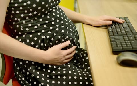 A pregnant office worker cradling her bump - Credit: Anthony Devlin/PA