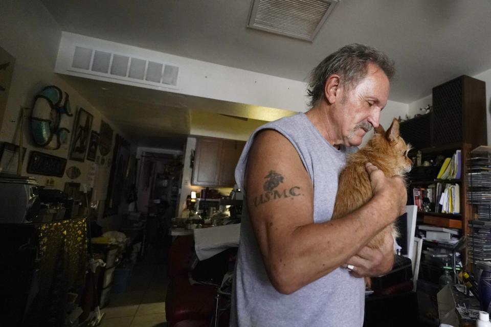 Rental resident Paul Wunder holds his dog Missy as he speaks about his eviction notice after meeting with Pima County Constable Kristen Randall Friday, Sept. 24, 2021, in Tucson, Ariz. Long delayed evictions are rolling out more than a month after the end of a federal moratorium that had protected tenants, including some who hadn't paid rent for many months during the coronavirus pandemic. (AP Photo/Ross D. Franklin)