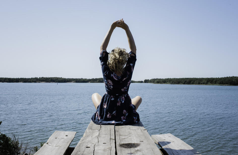 woman stretching whilst meditating in front of the sea