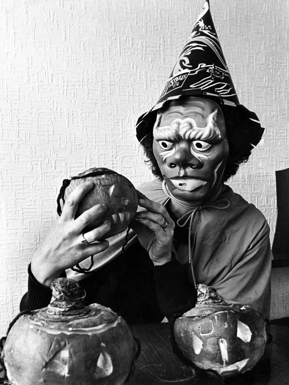 <p>A spooky masked witch carves turnip lanterns for a Halloween party<span> in 1987.</span></p>