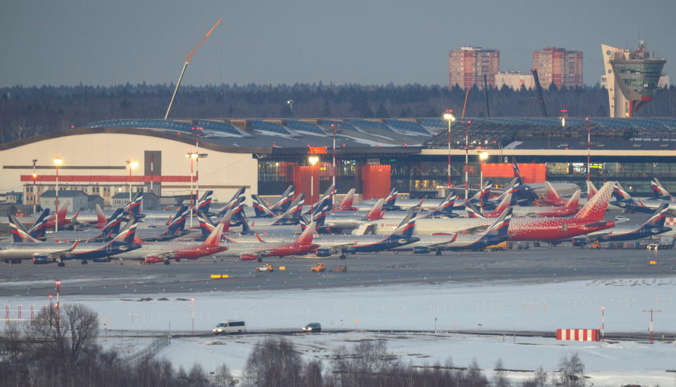 Dozens of passenger planes parked in tandem on the airport tarmac.