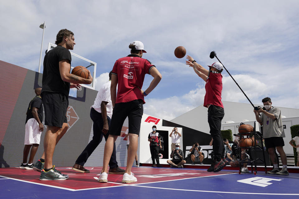 Former NBA player Fabricio Oberto, left, watches as Alfa Romeo drivers Antonio Giovinazzi, of Italy, center, and Kimi Raikkonen, of Finland, right, shoot free throws at the Formula One U.S. Grand Prix auto race at the Circuit of the Americas, Thursday, Oct. 21, 2021, in Austin, Texas. F1 Teams took part in a free throw challenge as to help the NBA celebrate their 75th Anniversary. (AP Photo/Eric Gay)