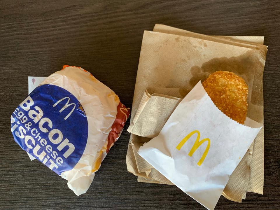 Mcdonald's packaged breakfast sandwich and hash browns on wooden table