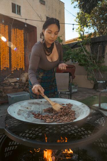 A woman roasts cacao in a comal