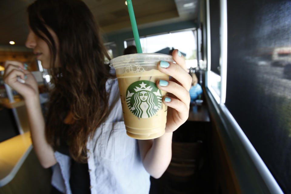 A patron holds an iced beverage at a Starbucks coffee store in Pasadena, California July 25, 2013. Starbucks Corp on Thursday posted a bigger than expected jump in quarterly profit after new fruit "Refresher" energy drinks and seasonal Frappuccino iced beverages helped drive more visits to shops in the United States, its top market. REUTERS/Mario Anzuoni (UNITED STATES - Tags: BUSINESS)