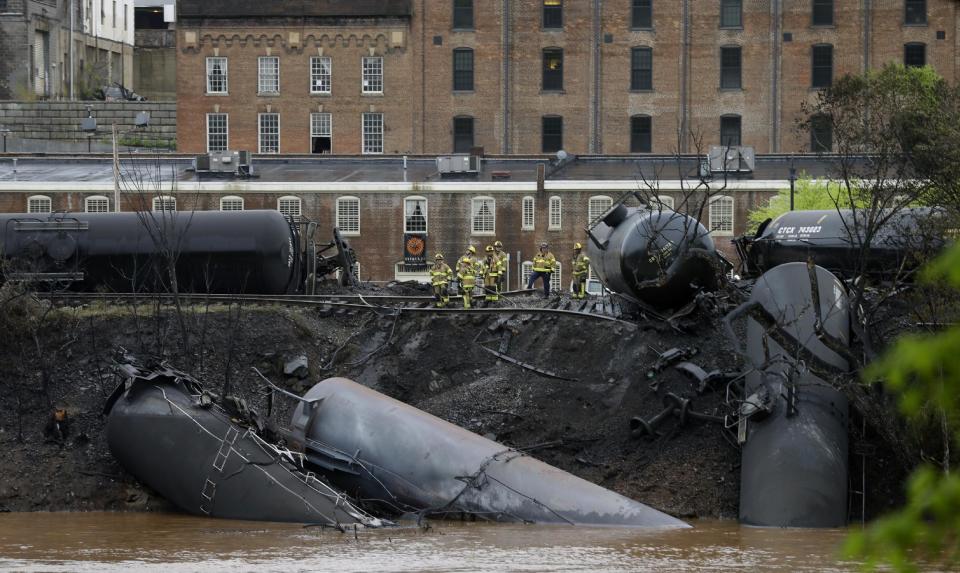 Firefighters and rescue workers work along the tracks where several CSX tanker cars carrying crude oil derailed and caught fire along the James River near downtown in Lynchburg, Va., Wednesday, April 30, 2014. Nearby buildings were evacuated for a time, but officials said there were no injuries and the city on its website and Twitter said firefighters on the scene made the decision to let the fire burn out. (AP Photo/Steve Helber)