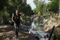 In this Dec. 11, 2012 photo, Tania Vera, 15, walks from her home alongside a polluted stream to practice with “The Orchestra of Instruments Recycled From Cateura” in Cateura, a vast landfill outside Paraguay's capital of Asuncion, Paraguay. I never thought my dreams would become reality,” said Vera, who lives in a wooden shack by a contaminated stream. Her mother has health problems, her father abandoned them, and her older sister left the orchestra after becoming pregnant. Tania, though, keeps to her goal of becoming a veterinarian as she keeps up with the music. (AP Photo/Jorge Saenz)