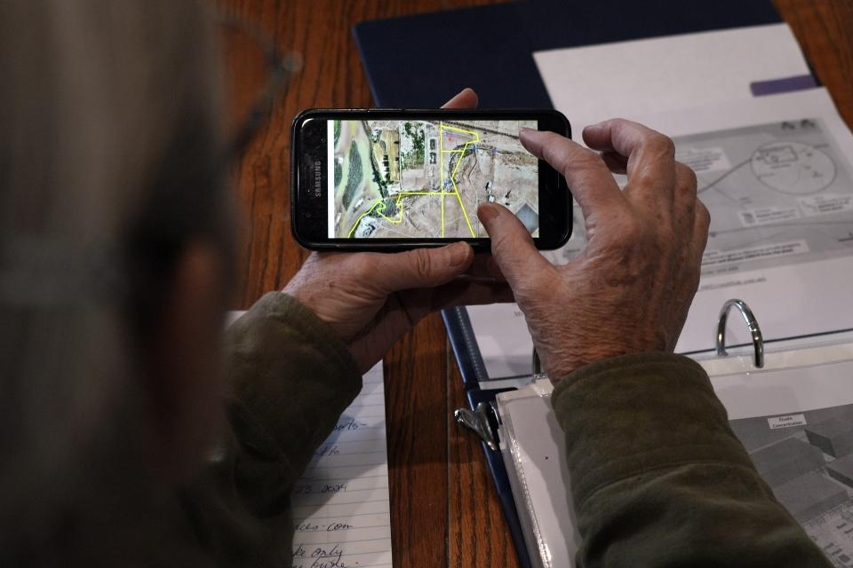 Gayna Salinas shows a map on her phone of land owned by Anson Resources, who plans to extract lithium, Thursday, Jan. 25, 2024, in Green River, Utah. The Australian company and its U.S. subsidiaries are eyeing the area to extract lithium, metal used in electric vehicle batteries. Salinas, whose family farms in the rural community, said she was skeptical about the project's benefits. (AP Photo/Brittany Peterson)
