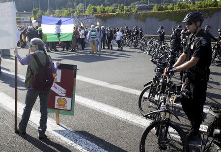 A line of police blocks protesters as they march and rally at the entrance of Terminal 5 at the Port of Seattle, Washington May 18, 2015. REUTERS/Jason Redmond