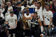 Milwaukee Bucks forward Giannis Antetokounmpo (34) reads with the championship trophy after defeating the Phoenix Suns in Game 6 of basketball's NBA Finals in Milwaukee, Tuesday, July 20, 2021. The Bucks won 105-98. (AP Photo/Paul Sancya)