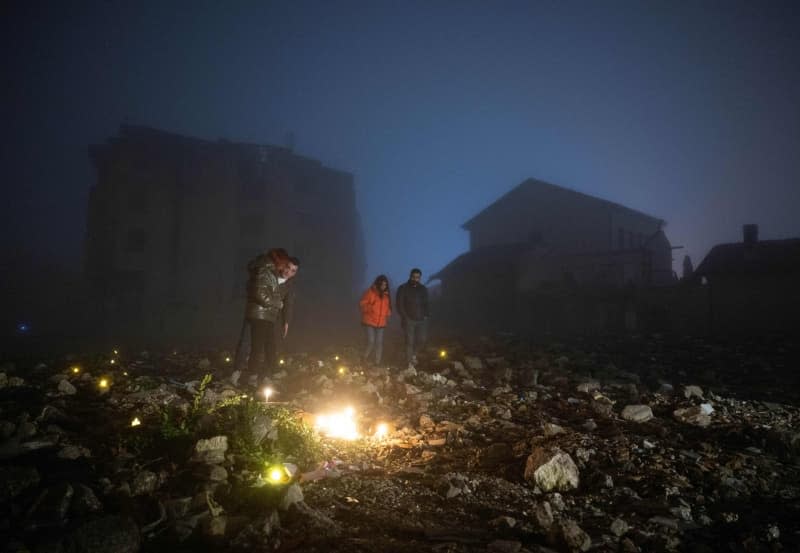 People light candles in the rubble of a house destroyed by the earthquake to remember their relatives who died there. As Turkey marks the first anniversary of the 7.8-magnitude quake that struck last year. Boris Roessler/dpa